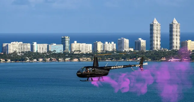 Helicopter releasing pink smoke over Miami skyline for a gender reveal