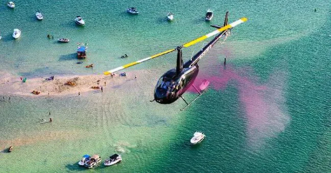 Aerial view of helicopter gender reveal over sandbar